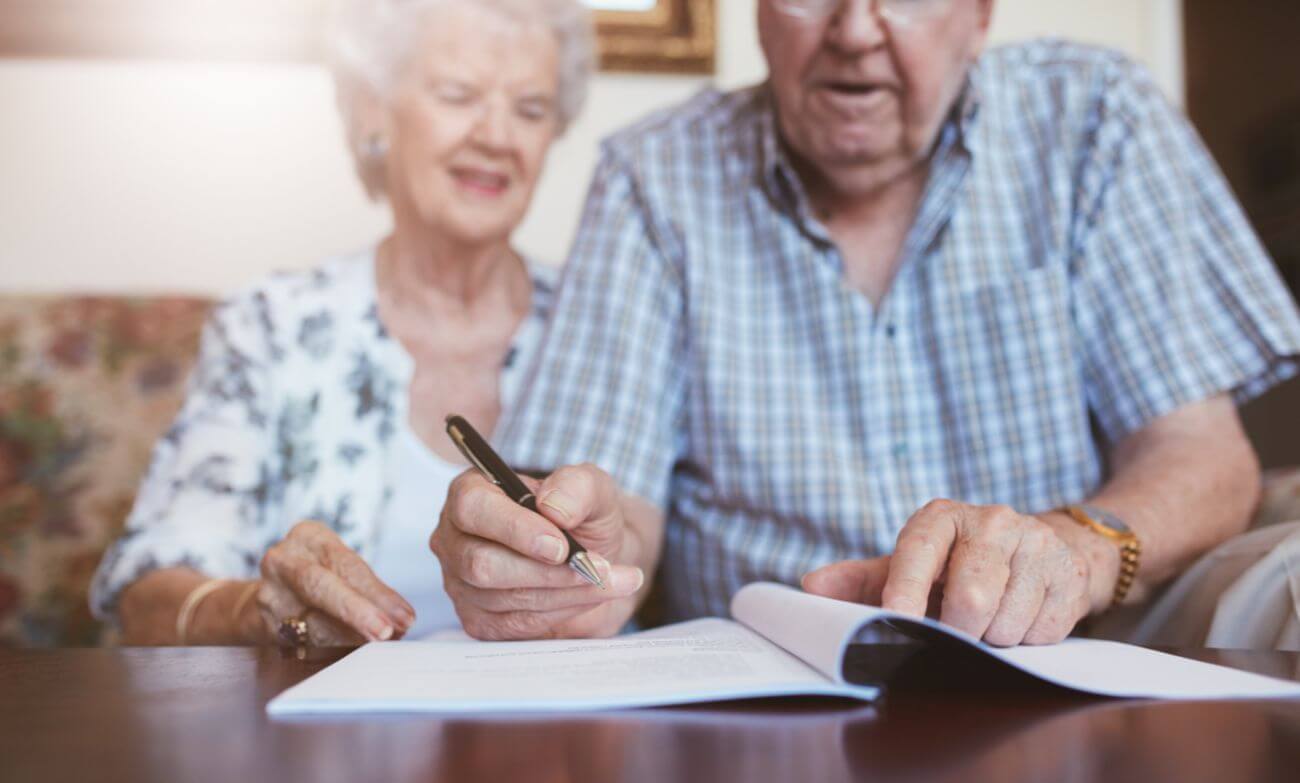 Foto de dos personas de tercera edad firmando unos documentos. Ilustra el artículo "¿Vivir en París y recibir una herencia española es posible?" de Martínez Lafuente Abogados